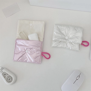 Quilted bow embroidery coin pouch with snap button shown with earbuds on a desk