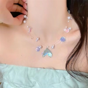 Detail of mermaid tail pendant necklace with iridescent blue finish and white pearls on neck