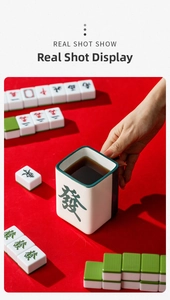 Close-up of a mahjong-shaped ceramic mug with green 'Fa' character held in hand