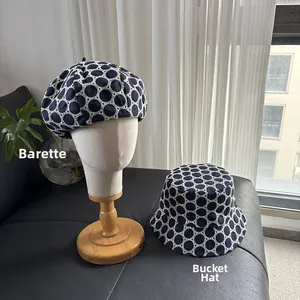 Detailed embroidery and polka dot patterns on navy blue beret and bucket hat models
