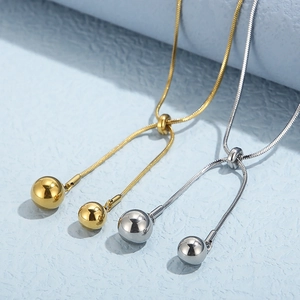 Detail view of adjustable gold and silver snake bone necklaces with metal ball pendants