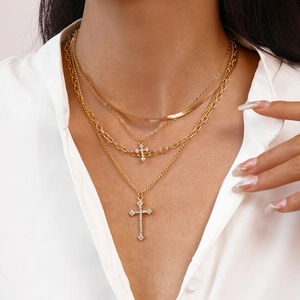 Layered gold cross pendant necklace with rhinestones on model with white shirt