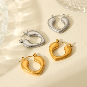 Flat lay of gold and silver hollow heart earrings on beige textured background with soft lighting