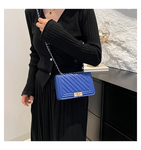 Blue quilted crossbody bag with gold chain strap and turn-lock shown with a model outfit