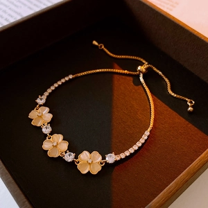 Detailed macro view of an adjustable gold flower bracelet with opal petals and zircons