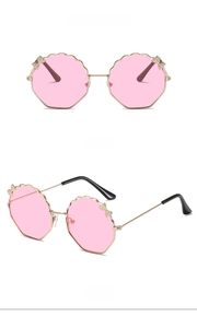 Détails de lunettes octogonales avec monture dorée, verres roses et nœud en diamant