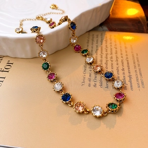 Detail of vintage Baroque necklace with colorful crystal stones on white ceramic plate