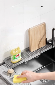 Detail of grey silicone sink splash guard with wave drainage pattern on black kitchen sink
