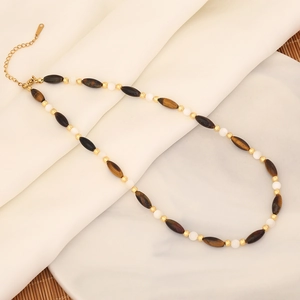 Detalle de cuentas de piedra de tigre y metal dorado sobre tela plisada beige
