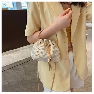 Detailed view of champagne gold rhinestone bucket bag with tassel drawstring and gold handles