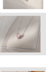 Close-up of pink heart gemstone necklace with silver chain on soft grey jewelry display