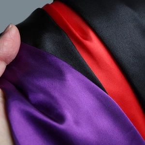 Detail of high-gloss purple, red, and black satin fabric texture for Halloween capes