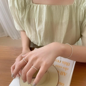 Minimalist 925 sterling silver 2mm bead bracelet and ring worn by a model in a cozy setting