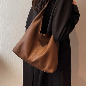 Brown leather large tote bag for women worn by a model in a minimalist style
