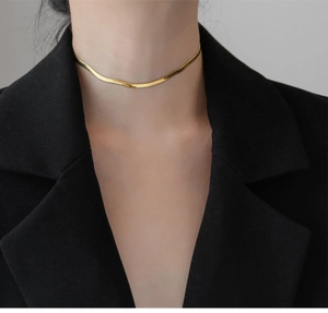 Close-up of a high-shine gold snake bone chain necklace worn with a black blazer