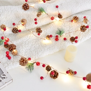 Christmas pine cone garland fairy lights with red berries and bells on white background