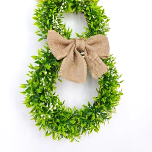 Detail view of bunny shaped green foliage wreath with a rustic burlap bow decoration
