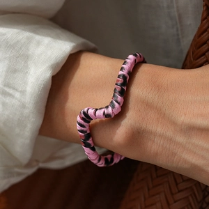 Detail shot of wavy leopard pattern fabric bracelet on wrist against aesthetic backdrop