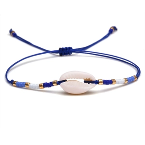Detail of adjustable blue woven bracelet featuring a natural white seashell and beads