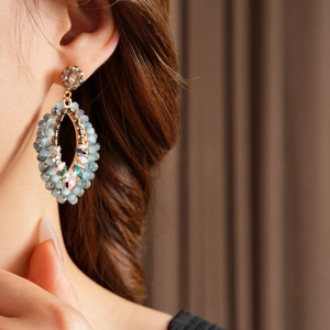 Gros plan de boucles d'oreilles bohèmes en perles bleues et cristaux sur modèle
