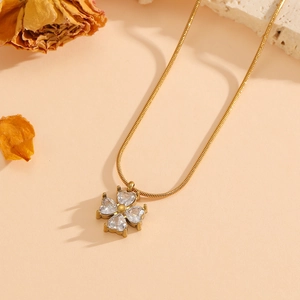 Collier trèfle à quatre feuilles doré avec cristaux en cœur sur fond de pierre naturelle