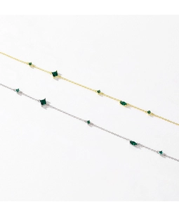 Detailed macro shot of vintage silver and gold necklaces with emerald green zircons