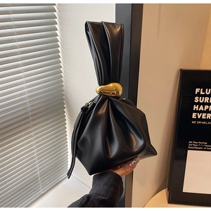Detail of black pleated bucket bag with a luxury gold pebble-shaped metal clasp