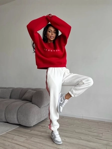 Women's red crewneck sweatshirt with embroidery paired with white side-striped joggers