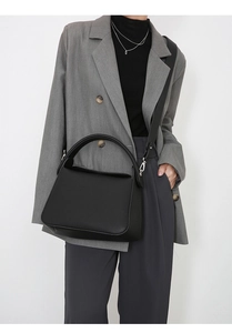 Model wearing black leather pillow bag with adjustable shoulder strap for daily commute