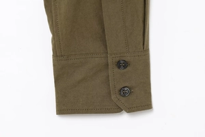 Detail shot of olive green shirt sleeve with double black buttons and cotton twill texture