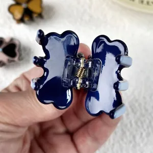 Small dark blue acetate clover hair claw clip with glossy finish and gold metal spring