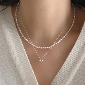 Close-up of layered 925 sterling silver heart necklace with irregular white pearls