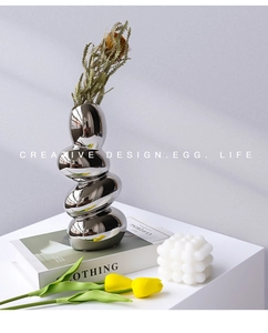 Close-up of stacked chrome pebble vase with mirror finish and dried floral decor