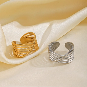 Minimalist interwoven stainless steel open rings in gold and silver on silk background