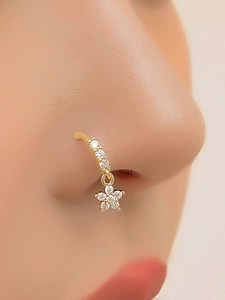 Gros plan d'un anneau de nez doré avec pendentif étoile et pierres claires sur un modèle