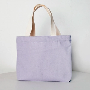 Detail of light purple canvas tote bag featuring cream webbing handles and fabric texture