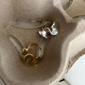 Anelli regolabili astratti a forma di onda in oro e argento su base di carta testurizzata