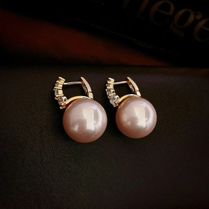 Vue macro de boucles d'oreilles perles roses avec créoles dorées serties de zircons fins