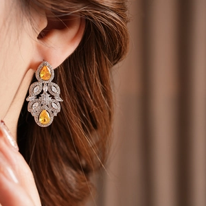 Close-up of vintage silver earrings with yellow pear-shaped zircon stones on a model