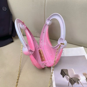 Detailed view of a crescent-shaped pink gradient acrylic evening bag with gold chain strap