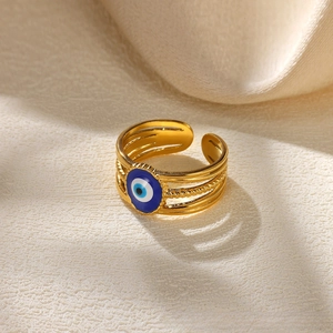 Macro shot of gold adjustable ring featuring a blue enamel evil eye and layered texture
