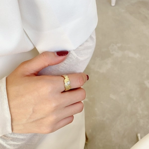 Close-up of a gold irregular textured silver ring featuring a clear zircon on a hand