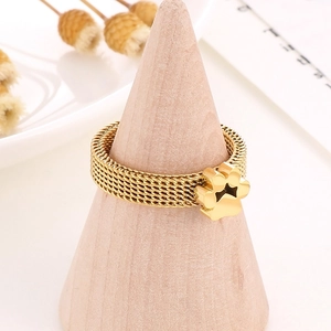 Macro view of golden mesh band ring with star-embossed cat paw charm on wooden stand