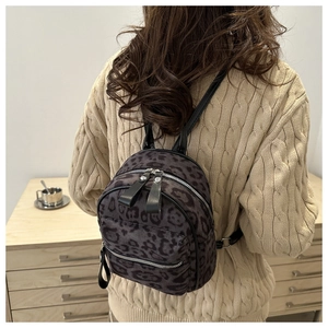 Mini leopard print backpack in dark grey worn on back over a beige knit sweater