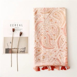 Ethnic paisley print shawl in orange coral hues with tassels on a minimalist white background