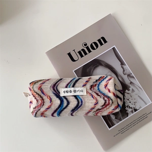 Détail du tissu en maille à vagues colorées et étiquette tissée sur pochette zippée