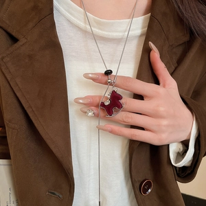 Detail of red flocked rocking horse lariat necklace with zircon on brown suede coat