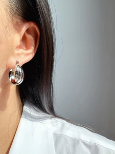 Close-up of a silver multi-layer layered geometric hoop earring worn by a model