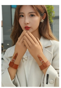 Detail of khaki suede gloves with brown leather wrist strap and decorative metal buckle
