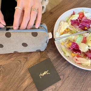 Macro shot of grey corduroy makeup bag with polka dots on a wooden cafe table